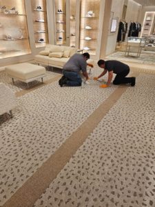 Two technicians from SOLID Surface Care providing professional commercial cleaning services by cleaning the carpet in a retail space.