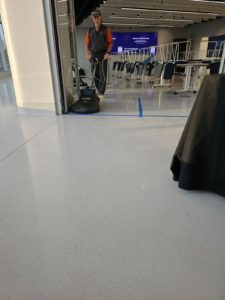 A technician from SOLID Surface Care polishing the floor in a retail environment as part of their comprehensive commercial cleaning services.