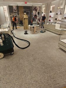 Three technicians from SOLID Surface Care providing professional commercial cleaning services by cleaning the carpet in a retail space.