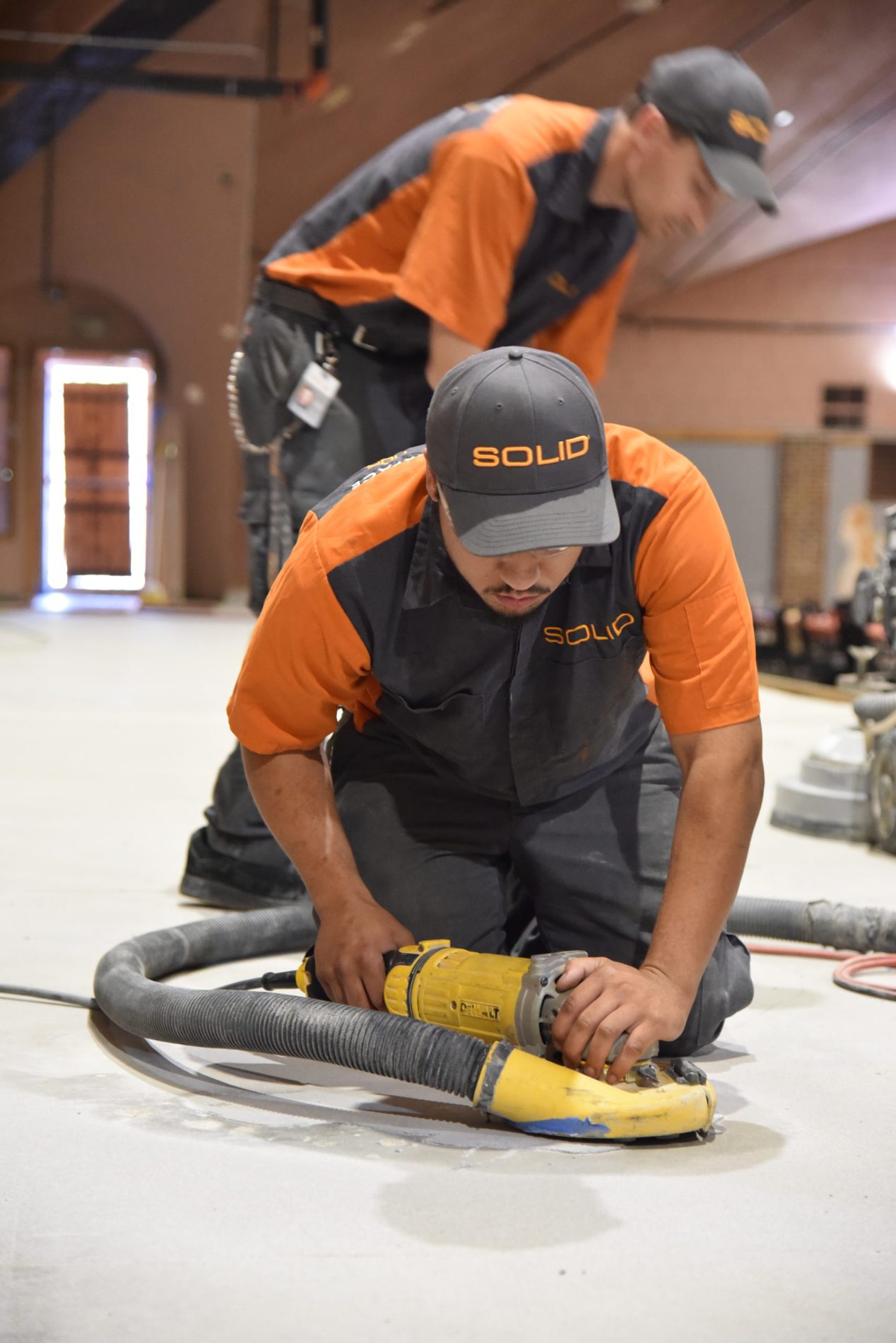 SOLID technician using a hand grinder on a concrete floor