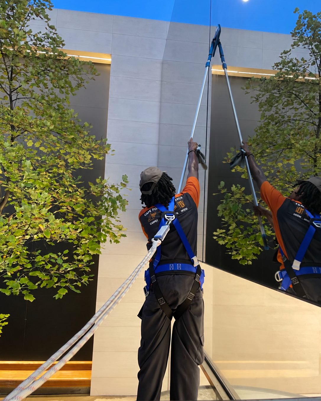 SOLID technician in a safety harness cleaning exterior glass with a water-fed pole