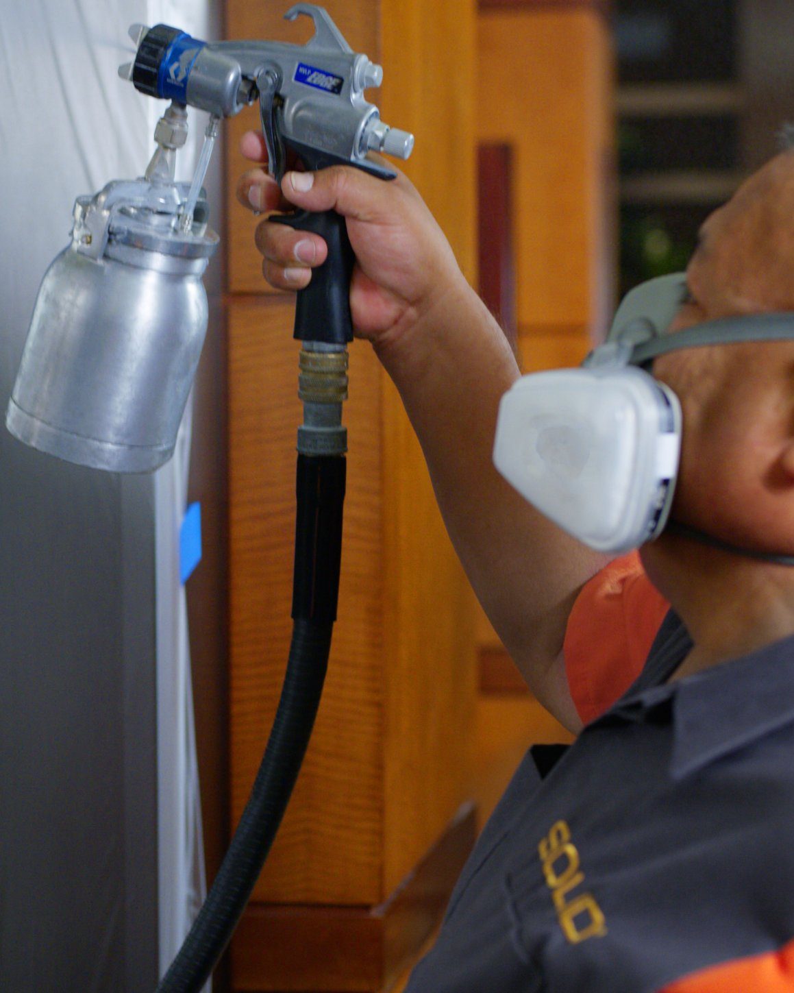SOLID technician in a respirator spraying a protective finish onto a metal surface