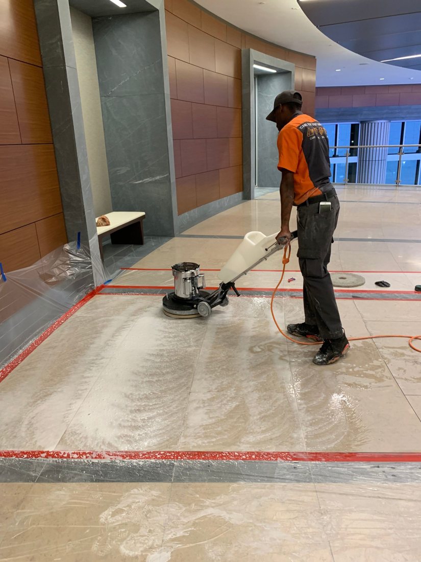 SOLID technician running a floor machine across a stone lobby floor